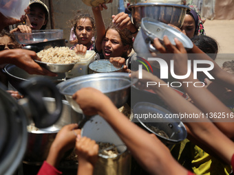 Displaced Palestinian children are waiting for food being distributed at a camp for internally displaced people where they are living due to...