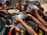 Displaced Palestinian children are waiting for food being distributed at a camp for internally displaced people where they are living due to...