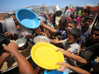 Displaced Palestinian children are waiting for food being distributed at a camp for internally displaced people where they are living due to...