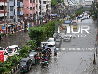 Vehicles and rickshaws are trying to drive with passengers through the waterlogged streets caused by heavy monsoon rainfalls in Dhaka, Bangl...