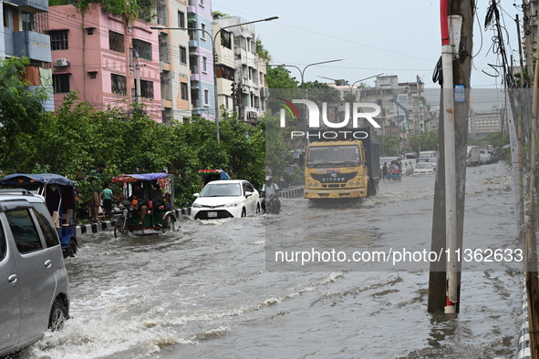 Vehicles and rickshaws are trying to drive with passengers through the waterlogged streets caused by heavy monsoon rainfalls in Dhaka, Bangl...