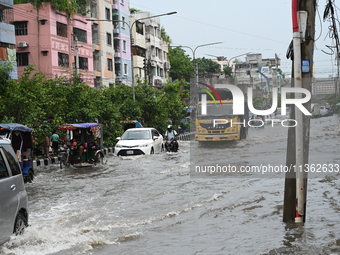 Vehicles and rickshaws are trying to drive with passengers through the waterlogged streets caused by heavy monsoon rainfalls in Dhaka, Bangl...