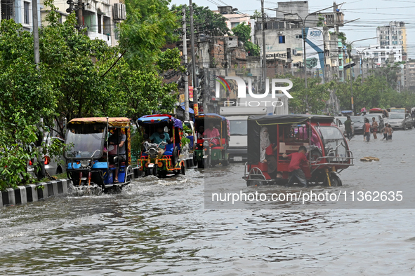 Vehicles and rickshaws are trying to drive with passengers through the waterlogged streets caused by heavy monsoon rainfalls in Dhaka, Bangl...