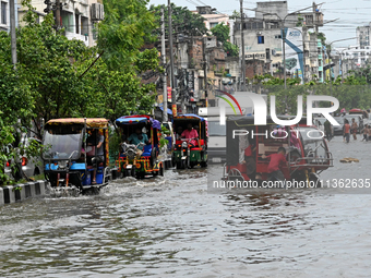 Vehicles and rickshaws are trying to drive with passengers through the waterlogged streets caused by heavy monsoon rainfalls in Dhaka, Bangl...