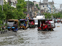 Vehicles and rickshaws are trying to drive with passengers through the waterlogged streets caused by heavy monsoon rainfalls in Dhaka, Bangl...