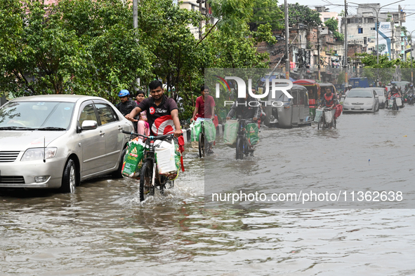 Vehicles and rickshaws are trying to drive with passengers through the waterlogged streets caused by heavy monsoon rainfalls in Dhaka, Bangl...