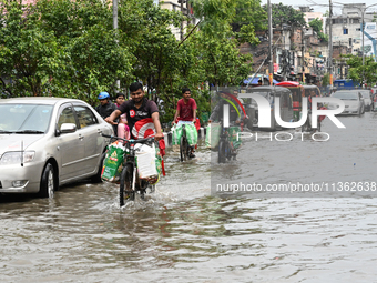 Vehicles and rickshaws are trying to drive with passengers through the waterlogged streets caused by heavy monsoon rainfalls in Dhaka, Bangl...