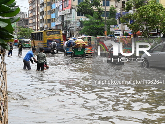 Vehicles and rickshaws are trying to drive with passengers through the waterlogged streets caused by heavy monsoon rainfalls in Dhaka, Bangl...