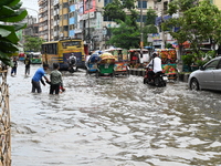 Vehicles and rickshaws are trying to drive with passengers through the waterlogged streets caused by heavy monsoon rainfalls in Dhaka, Bangl...