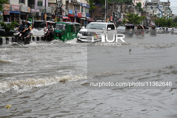 Vehicles and rickshaws are trying to drive with passengers through the waterlogged streets caused by heavy monsoon rainfalls in Dhaka, Bangl...