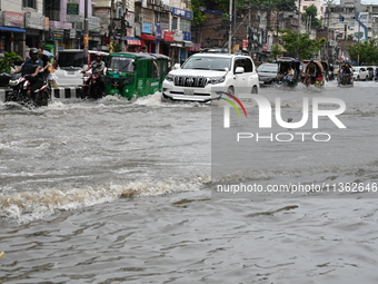 Vehicles and rickshaws are trying to drive with passengers through the waterlogged streets caused by heavy monsoon rainfalls in Dhaka, Bangl...