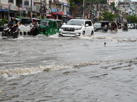 Vehicles and rickshaws are trying to drive with passengers through the waterlogged streets caused by heavy monsoon rainfalls in Dhaka, Bangl...