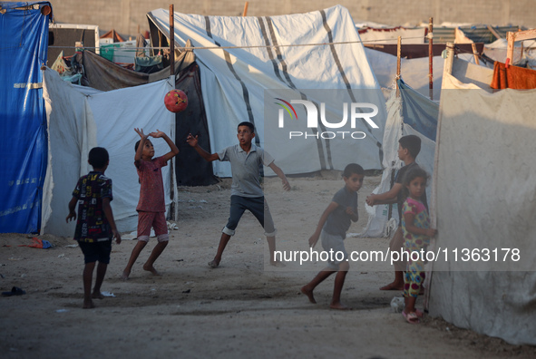 Displaced Palestinian children are playing football at a camp for displaced Palestinians in Deir al-Balah, in the central Gaza Strip, on Jun...