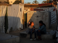 Displaced Palestinian girls are sitting at a camp for displaced Palestinians in Deir al-Balah, in the central Gaza Strip, on June 26, 2024,...