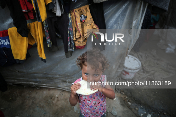 A displaced Palestinian girl is standing outside her tent at a camp for displaced Palestinians in Deir al-Balah, in the central Gaza Strip,...