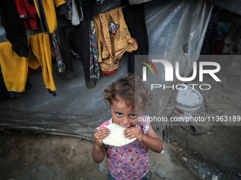 A displaced Palestinian girl is standing outside her tent at a camp for displaced Palestinians in Deir al-Balah, in the central Gaza Strip,...