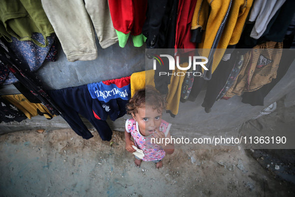 A displaced Palestinian girl is standing outside her tent at a camp for displaced Palestinians in Deir al-Balah, in the central Gaza Strip,...