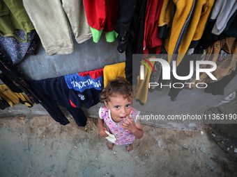 A displaced Palestinian girl is standing outside her tent at a camp for displaced Palestinians in Deir al-Balah, in the central Gaza Strip,...