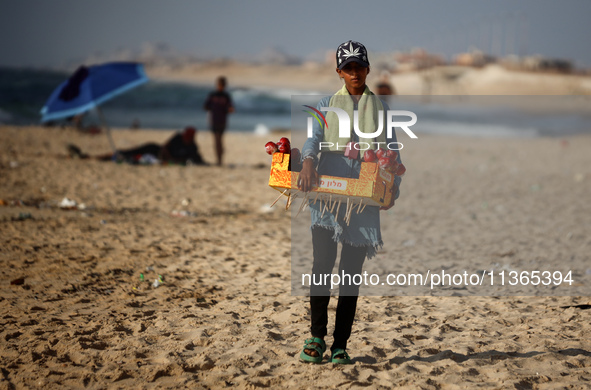 A Palestinian girl is selling candied apples as Palestinians are spending time at the beach on a hot summer day in Nuseirat in the central G...