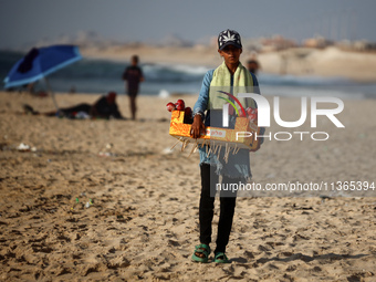 A Palestinian girl is selling candied apples as Palestinians are spending time at the beach on a hot summer day in Nuseirat in the central G...