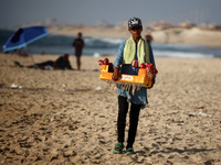 A Palestinian girl is selling candied apples as Palestinians are spending time at the beach on a hot summer day in Nuseirat in the central G...