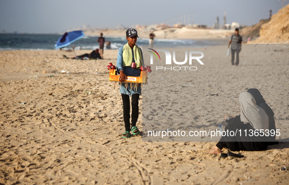 A Palestinian girl is selling candied apples as Palestinians are spending time at the beach on a hot summer day in Nuseirat in the central G...