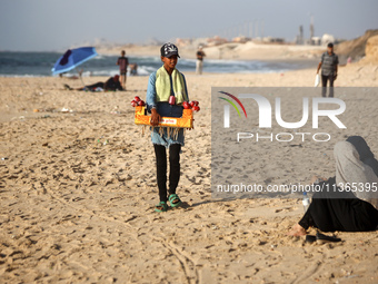 A Palestinian girl is selling candied apples as Palestinians are spending time at the beach on a hot summer day in Nuseirat in the central G...