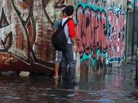 Two people are trying to cross a flooded street in the municipality of Nezahualcoyotl due to the heavy rains recorded yesterday, on June 27,...