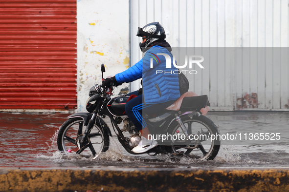 A person is riding a motorcycle on a flooded street in the municipality of Nezahualcoyotl due to the heavy rains recorded yesterday in Mexic...