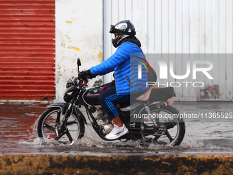 A person is riding a motorcycle on a flooded street in the municipality of Nezahualcoyotl due to the heavy rains recorded yesterday in Mexic...