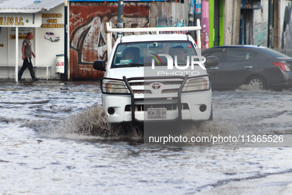 A driver is crossing a flooded street in the municipality of Nezahualcoyotl due to the heavy rains recorded yesterday, on June 27, 2024, in...