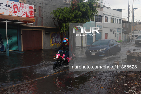 A person is riding a motorcycle on a flooded street in the municipality of Nezahualcoyotl due to the heavy rains recorded yesterday in Mexic...