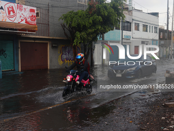 A person is riding a motorcycle on a flooded street in the municipality of Nezahualcoyotl due to the heavy rains recorded yesterday in Mexic...