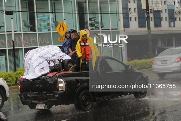 Workers are wearing waterproofs to cover themselves from the heavy rains on the Calzada Ermita south of the city, due to Tropical Wave Numbe...