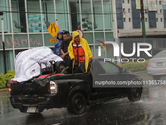 Workers are wearing waterproofs to cover themselves from the heavy rains on the Calzada Ermita south of the city, due to Tropical Wave Numbe...