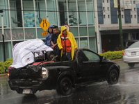 Workers are wearing waterproofs to cover themselves from the heavy rains on the Calzada Ermita south of the city, due to Tropical Wave Numbe...