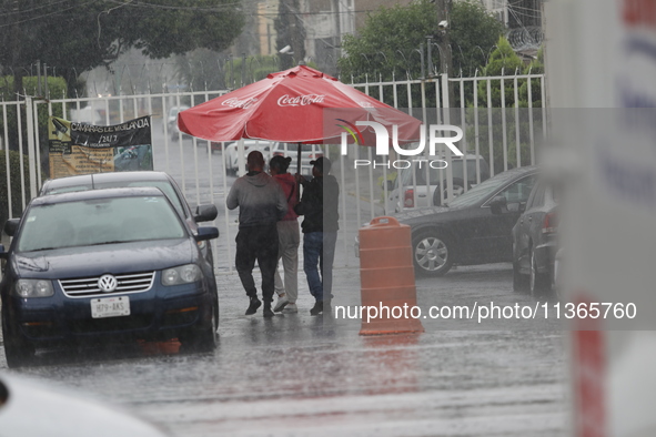 Persons are covering themselves with an umbrella from the heavy rains on the Calzada Ermita south of the city, due to Tropical Wave Number 5...