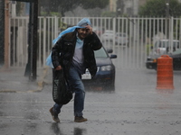 A man is wearing a waterproof to cover himself from the heavy rains on the Calzada Ermita south of the city, due to Tropical Wave Number 5,...