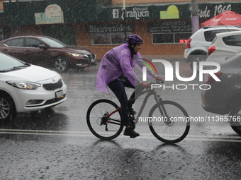 A woman is riding a bicycle wearing a waterproof to cover herself from the heavy rains on the Calzada Ermita south of the city, due to Tropi...