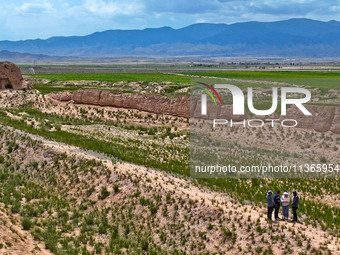 Workers are conducting an on-site survey and data collection of trenches and walls at the narrowest part of the Great Wall of the Han and Mi...