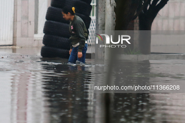 A woman is trying to walk with water above her knees on Vicente Villada Avenue, which is flooded due to heavy rains in the Municipality of N...