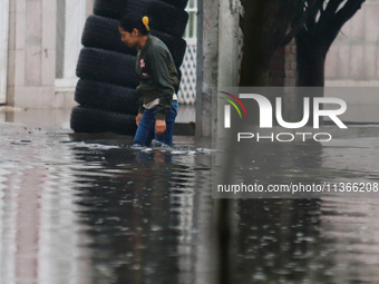 A woman is trying to walk with water above her knees on Vicente Villada Avenue, which is flooded due to heavy rains in the Municipality of N...