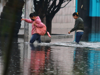 Women are walking with their legs submerged in the water, trying to cross Vicente Villada Avenue, which is flooded due to the heavy rains th...