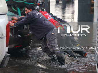 Municipality workers are pushing a stranded vehicle due to the heavy rains that are hitting Mexico. Vicente Villada Avenue in the Municipali...