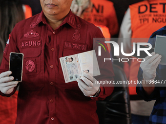 Indonesian immigration authorities are showing handphones and a Taiwan national passport during a press conference at the Immigration Detent...