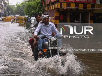 A man is riding his bike through a flooded street after heavy rains in New Delhi, India, on June 28, 2024. (