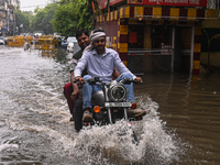 A man is riding his bike through a flooded street after heavy rains in New Delhi, India, on June 28, 2024. (