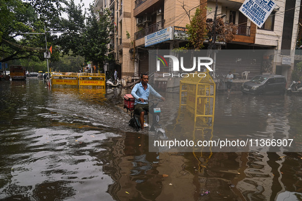 A food delivery person is riding his electric bike through a flooded street after heavy rains in New Delhi, India, on June 28, 2024. 