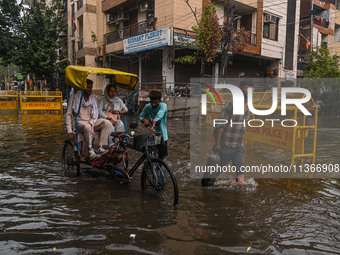 People are wading through a flooded street after heavy rains in New Delhi, India, on June 28, 2024. (