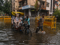 People are wading through a flooded street after heavy rains in New Delhi, India, on June 28, 2024. (